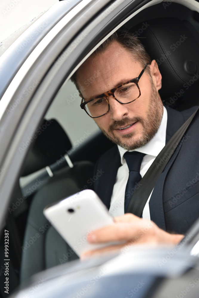 Businessman in car reading message on smartphone Businessman in car reading message on smartphone
