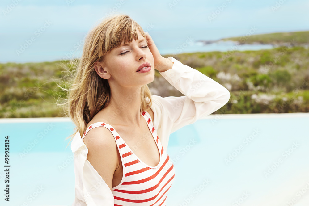 Serene young woman at poolside, eyes closed