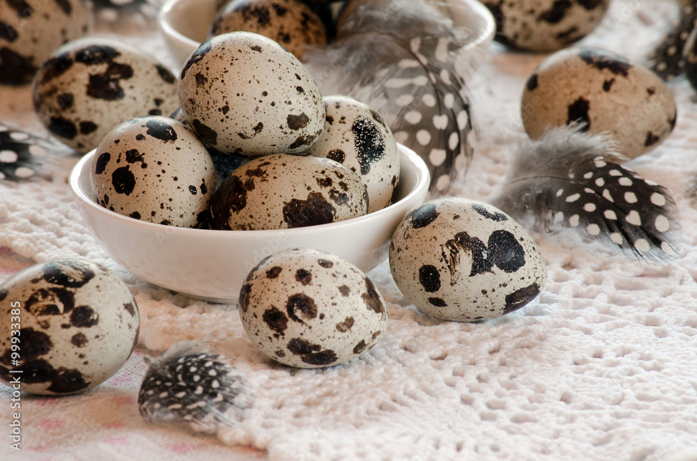 Fototapeta premium Quail eggs on a platter on the table and feathers