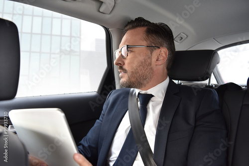 Businessman in taxi cab reading news on digital tablet © goodluz