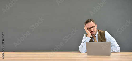 Middle aged man being bored in front of laptop, isolated