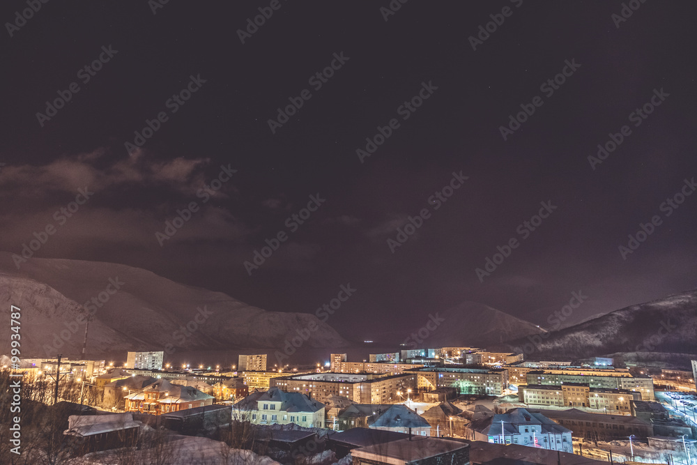 Small town situated in the foot of the mountain against background with mountains at night