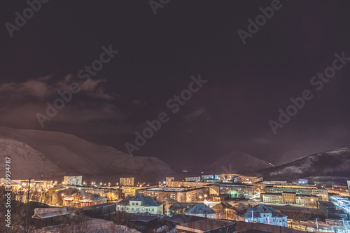 Small town situated in the foot of the mountain against background with mountains at night © drdonut