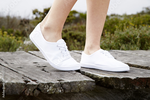 White sneakers on model walking on boardwalk  close up