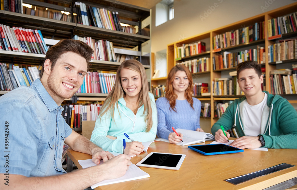 happy students writing to notebooks in library happy students writing to notebooks in library