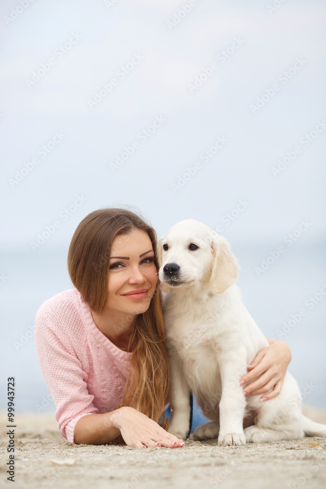 A young woman near the sea with a puppy Retriever A young woman near the sea with a puppy Retriever