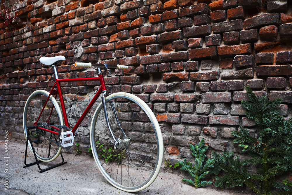Red fixie bike, in front of a red brick wall.