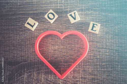 Love concept. Valentines day background with red heart and Love message written in wooden blocks