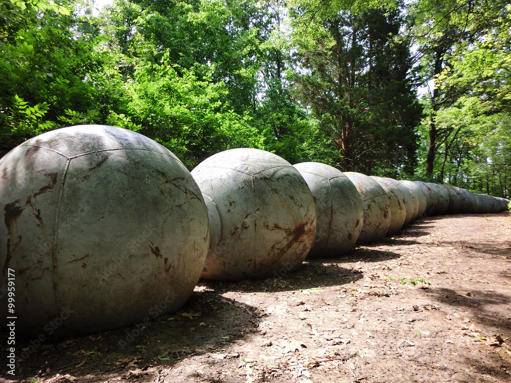 Concrete balls aligning forest path in daylight Concrete balls aligning forest path in daylight