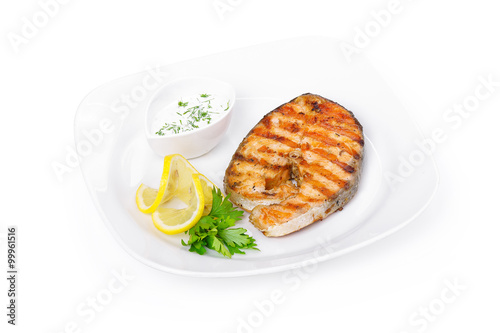 Grilled salmon steak with sauce and lemon