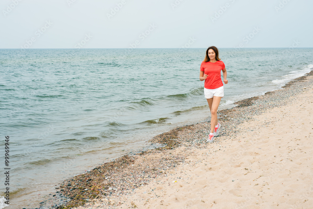 Woman running by the sea in an orange T-shirt