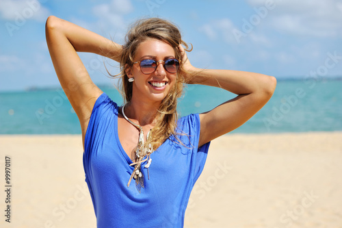 Young beautiful blonde woman in blue dress posing outdoors in su