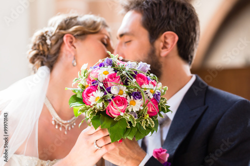 Bridal couple giving kiss in church at wedding photo