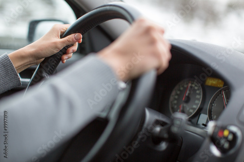 Driver's hands driving a car on a highway 