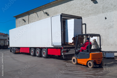 Worker on the loader unload white semi-trailer
