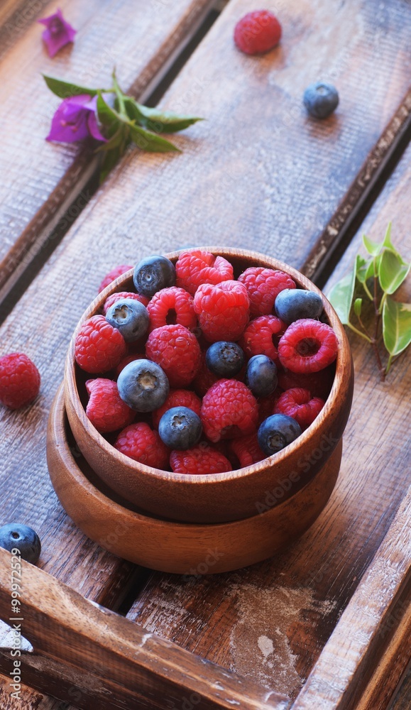 Blueberries and raspberries in bowl, on a wooden background, selective focus
