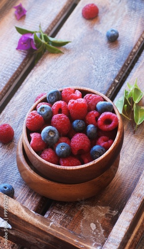 Fototapeta Naklejka Na Ścianę i Meble -  Blueberries and raspberries in bowl, on a wooden background, selective focus
