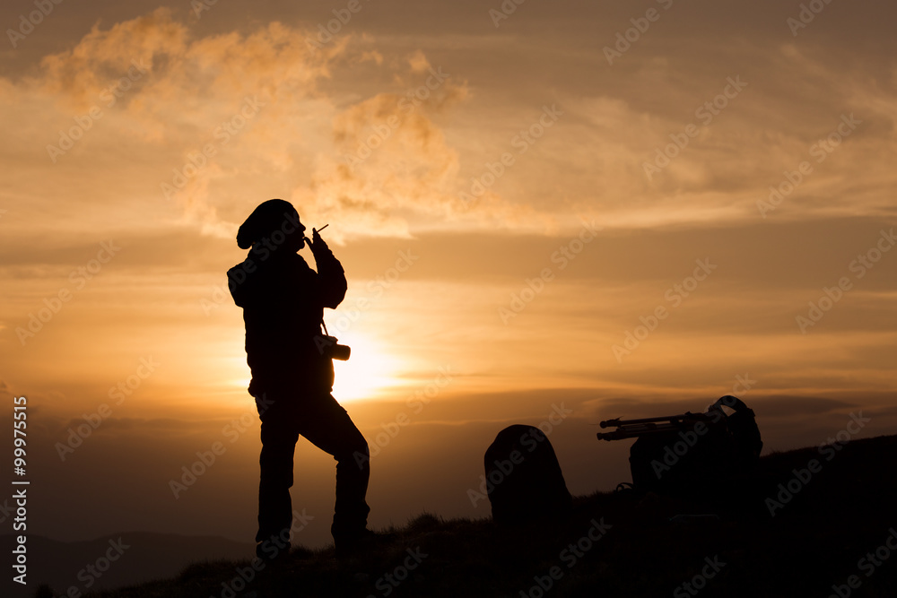Silhouette of woman photographer smoking at sunset
