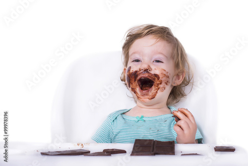 Adorable kid eating chocolate with face covered in chocolate