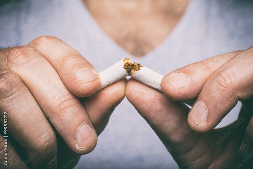 Quitting smoking - male hand crushing cigarette - obrazy, fototapety, plakaty 