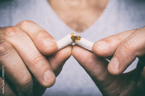 Quitting smoking - male hand crushing cigarette photo