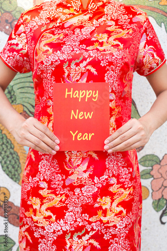 Happy Chinese new year Asian woman with red Cheongsam holding a red packet wishing you Happy New Year on chinese pattern traditional background © powerbeephoto