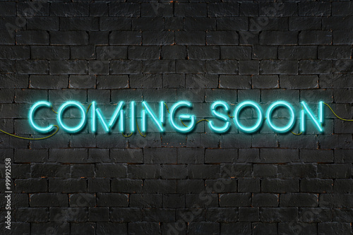 "COMING SOON" neon sign shining on black brick wall,Business con