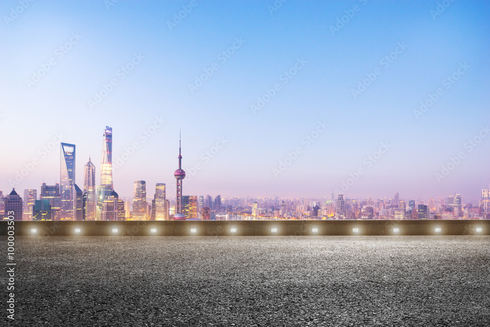 empty asphalt road and cityscape in blue sky at dawn