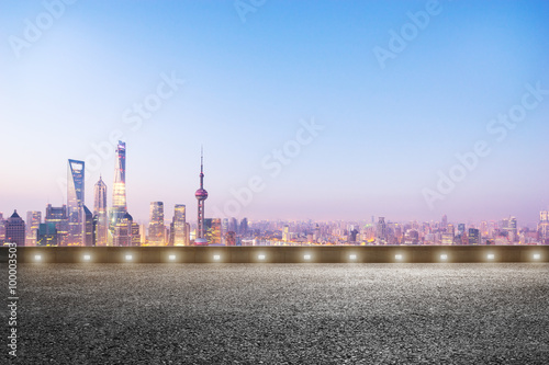 empty asphalt road and cityscape in blue sky at dawn © zhu difeng