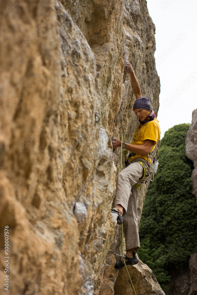 Young male climber hanging on a cliff with a rope.