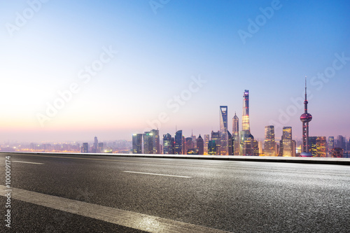 empty asphalt road and cityscape in blue sky at dawn © zhu difeng