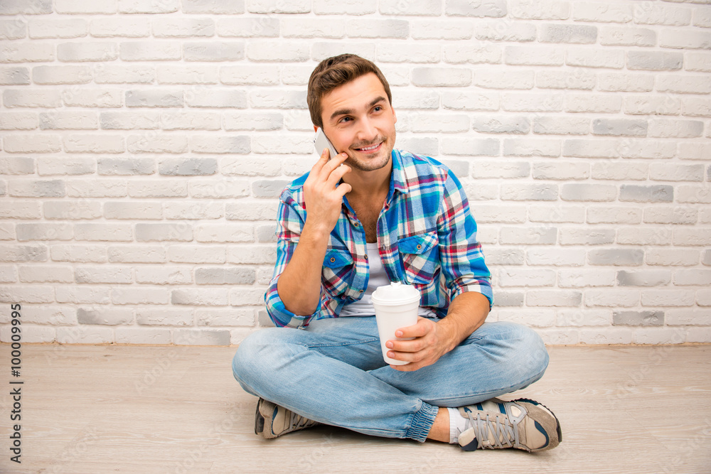 Handsome man sitting on the floor with crossed legs and holding Handsome man sitting on the floor with crossed legs and holding