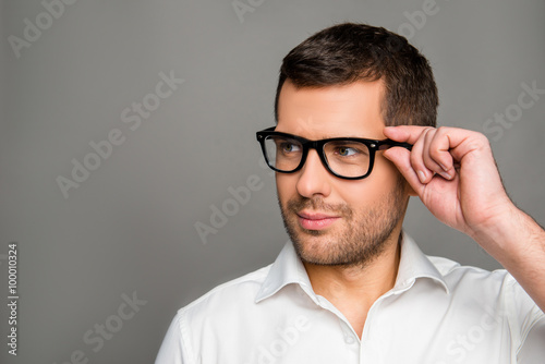 Fototapeta Naklejka Na Ścianę i Meble -  Smart man  touching his glasses and looking ahead