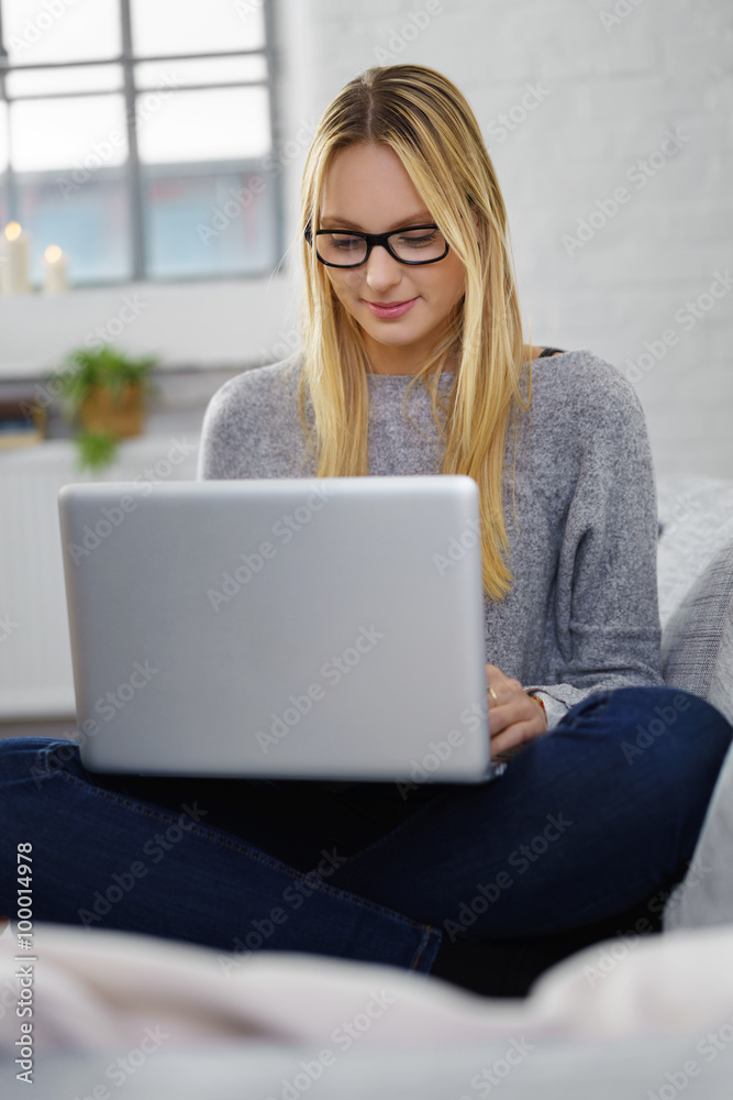 frau sitzt im schneidersitz auf dem sofa und arbeitet am laptop frau sitzt im schneidersitz auf dem sofa und arbeitet am laptop