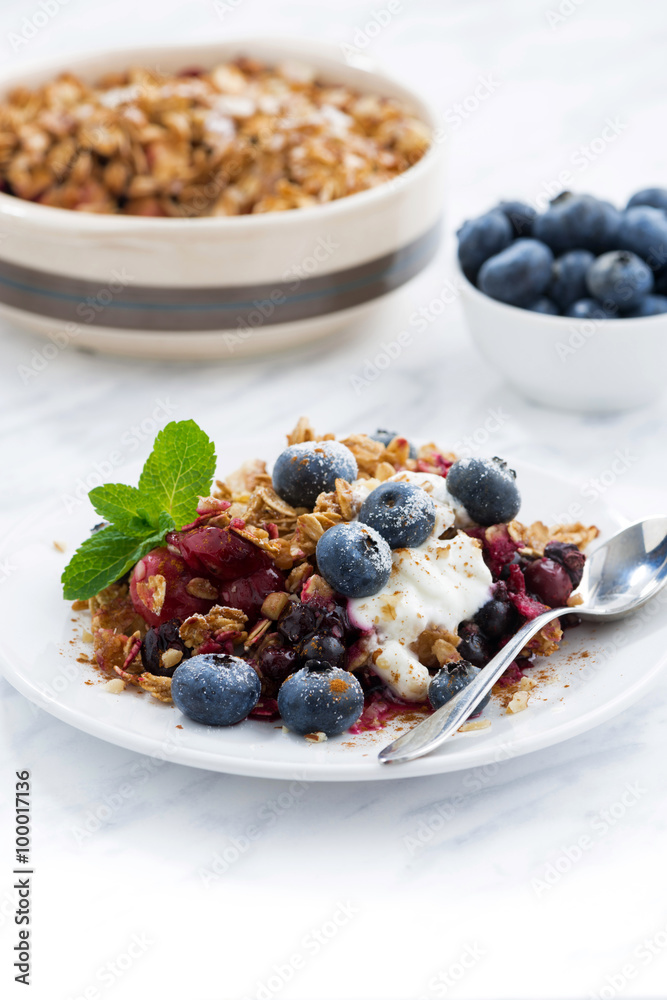 berry crumble with oat flakes, cream and blueberries