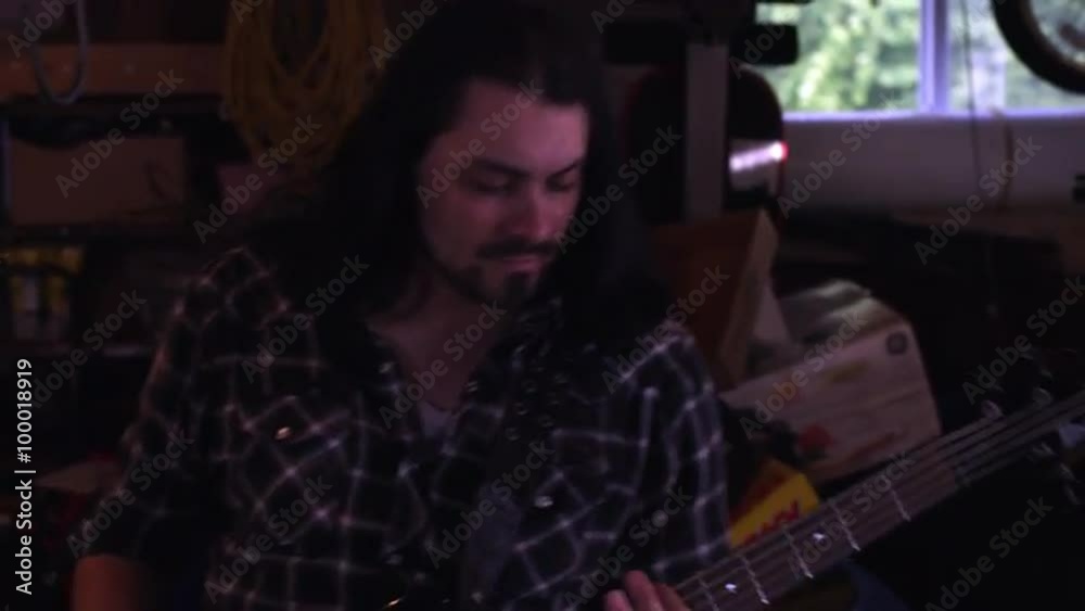 Handheld shot of a long-haired man playing a bass guitar Handheld shot of a long-haired man playing a bass guitar