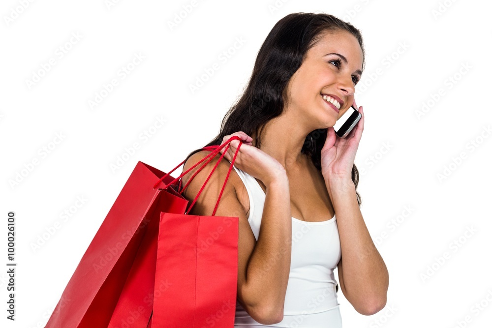 Smiling woman holding shopping bagsand using smartphone