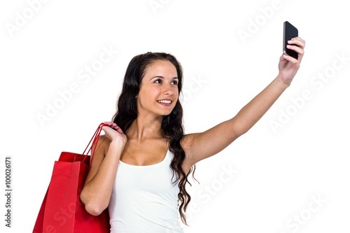 Smiling woman holding shopping bags taking selfie
