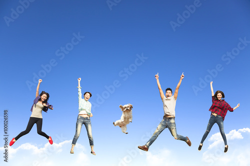 happy young group jumping together with dog