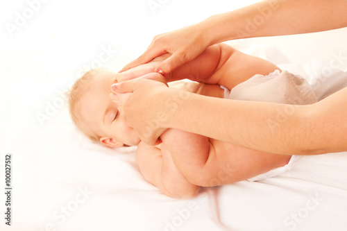 Baby massage. Baby feet touching his forehead.