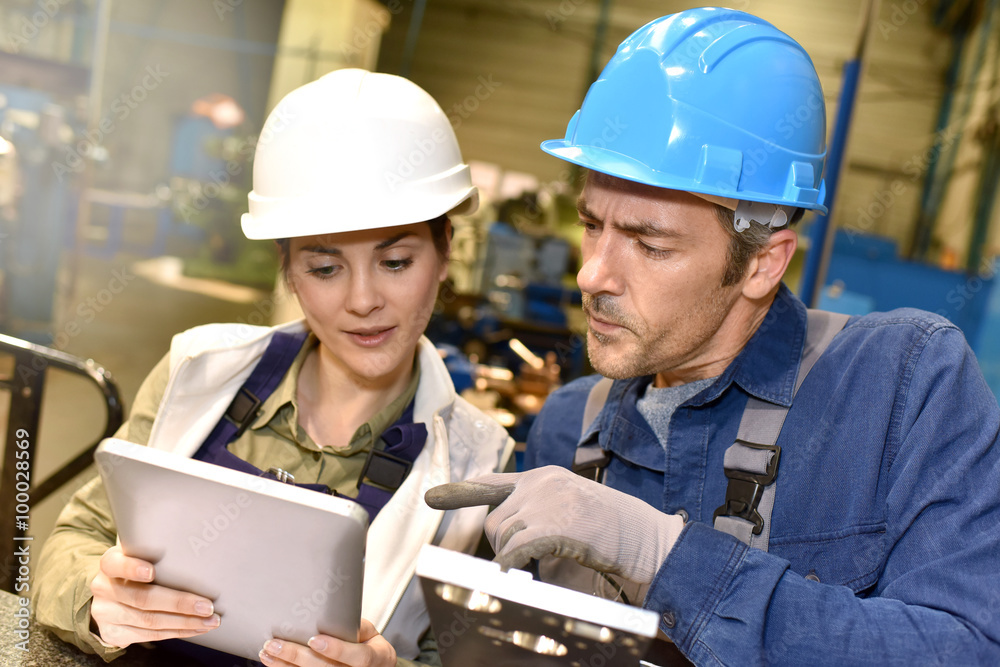 Metallurgy workers in workshop using digital tablet Metallurgy workers in workshop using digital tablet