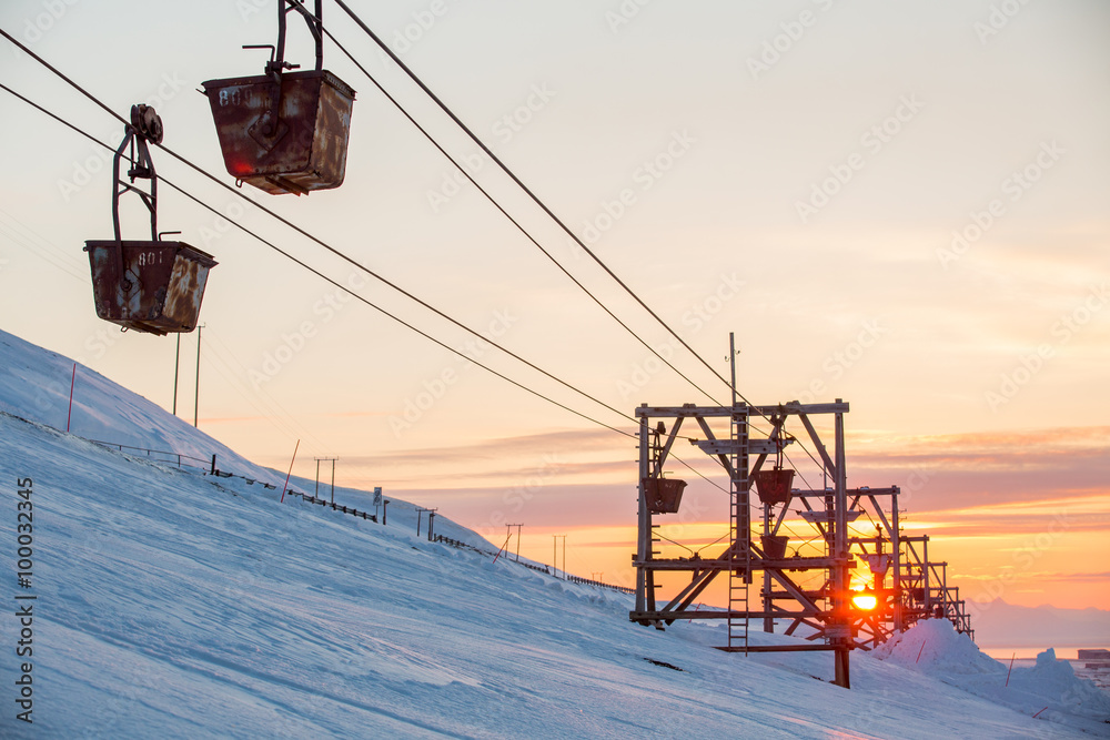 Old abandoned coal cableway in the rays of the setting sun in the town of Longyearbyen among snow-capped mountains of the Norwegian archipelago of Svalbard Old abandoned coal cableway in the rays of the setting sun in the town of Longyearbyen among snow-capped mountains of the Norwegian archipelago of Svalbard