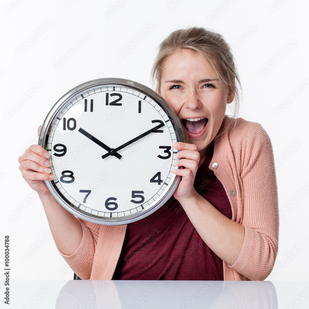 time concept - ecstatic beautiful young blond woman holding a clock,laughing for fun and impatience, white background.