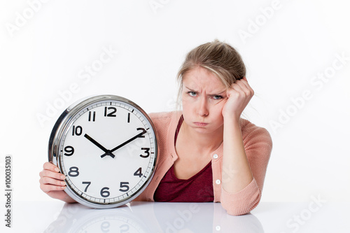 time concept - complaining beautiful young blond woman holding a clock unhappy and frustrated by future, white background