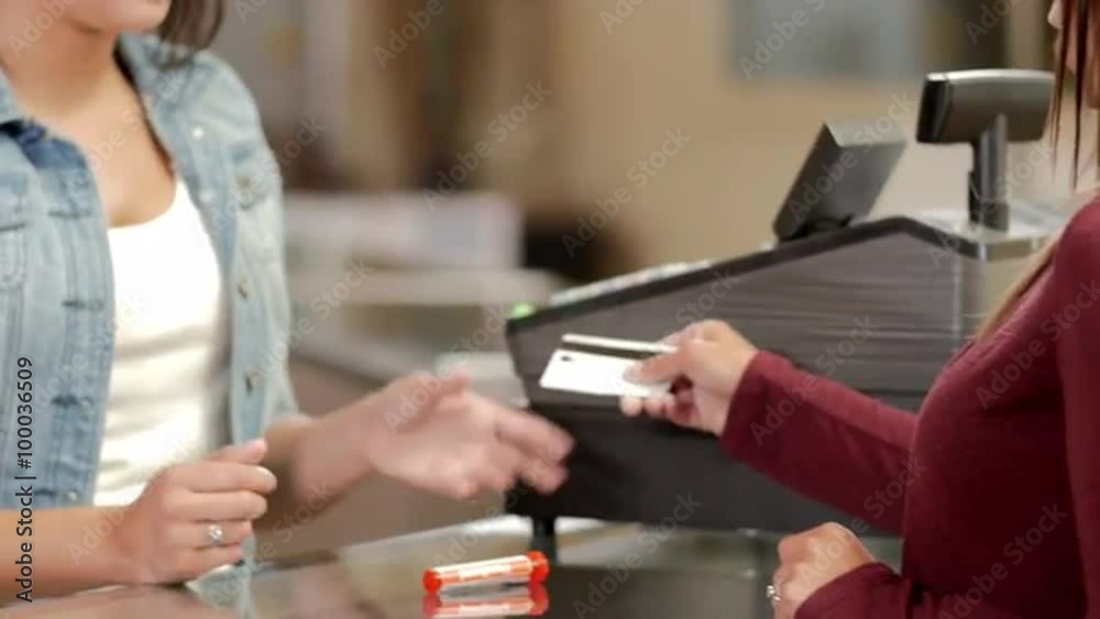 Associate at a recreational marijuana shop ringing up a purchase with a debit or credit card