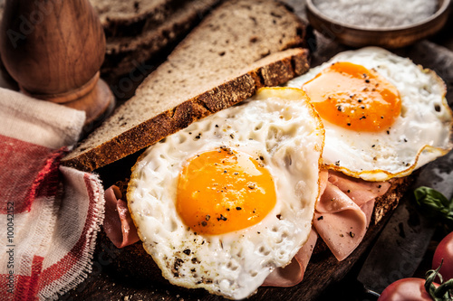Seasoned fried eggs and ham on whole grain bread photo