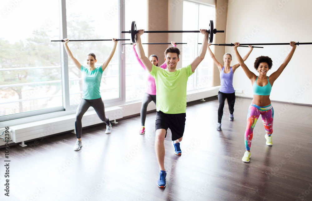 Naklejka premium group of people exercising with bars in gym