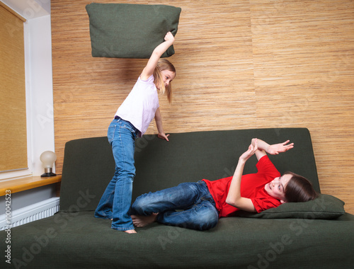 Foto Brother and sister wearing casual clothes playing on a green sofa at home fighti