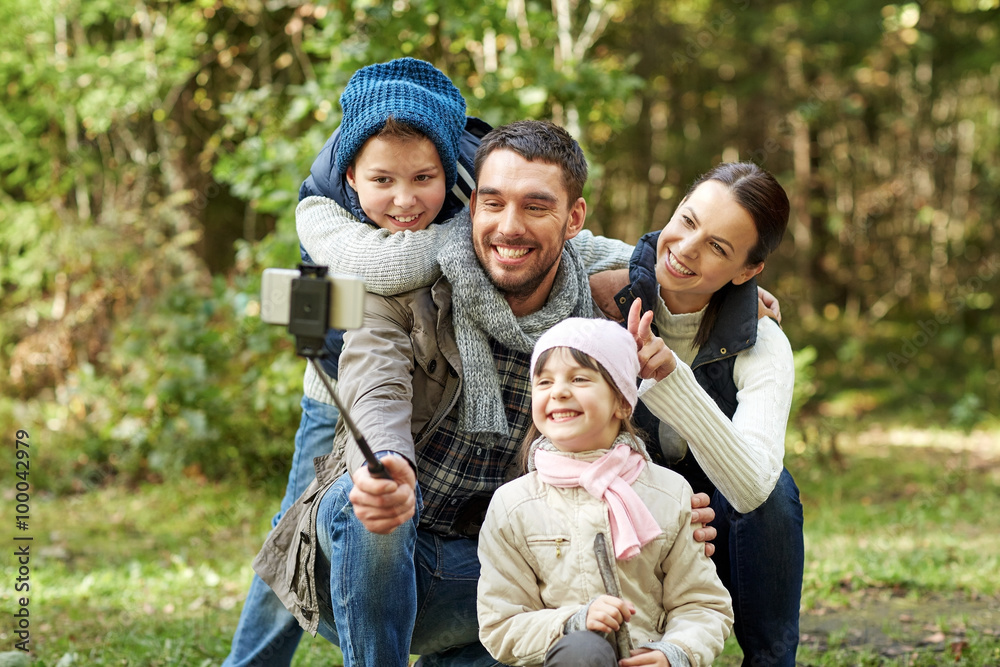 happy family with smartphone selfie stick in woods