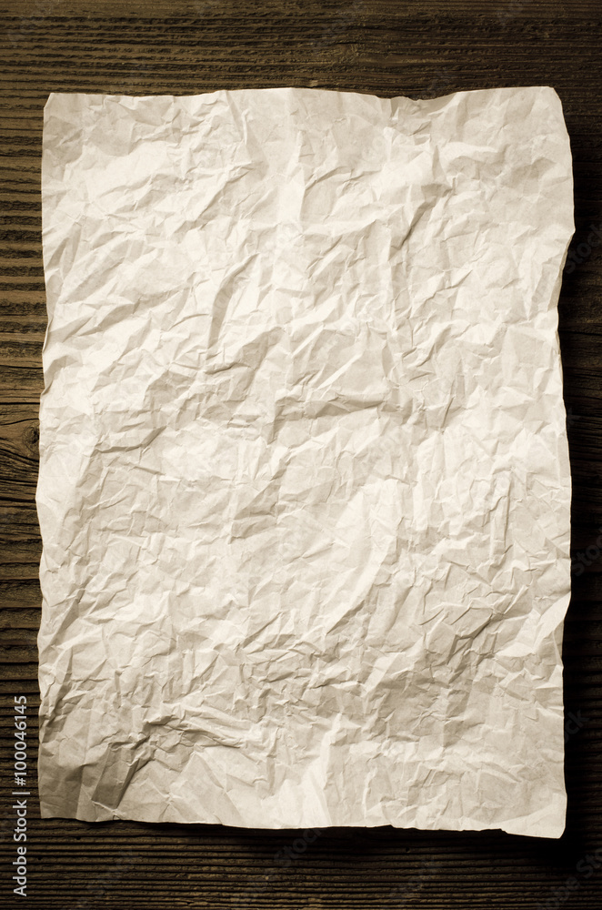Sheet of crumpled paper on wooden table Sheet of crumpled paper on wooden table